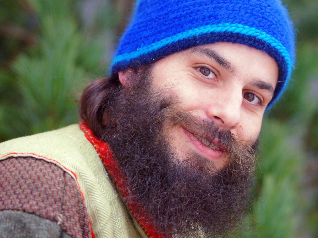 Portrait of an outdoors-y man with a beard and a blue beanie on